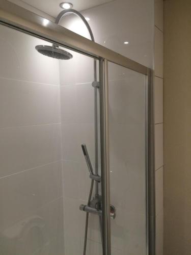 a shower stall with a glass door with a shower at Edinburgh West Side Hostel in Edinburgh