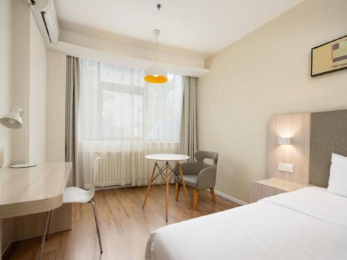 ein Schlafzimmer mit einem Bett, einem Schreibtisch und einem Tisch in der Unterkunft Hanting Hotel Beijing Daxing New Town Jinxing Bridge in Peking