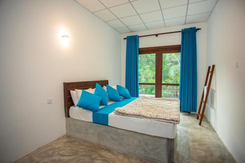 a bedroom with a bed with blue pillows and a window at Amora Villa in Galle