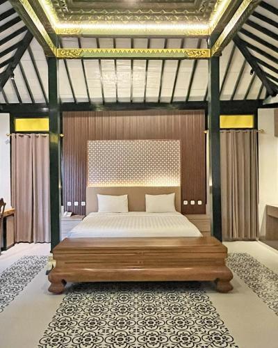 a bedroom with a large bed with a wooden frame at The Amrta Borobudur in Borobudur