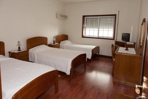 een ziekenhuiskamer met 2 bedden en een televisie bij Residencial O TRINDADE in Águeda