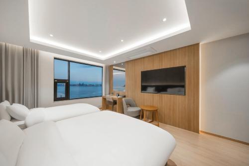 - une chambre blanche avec un grand lit et une grande fenêtre dans l'établissement Pohang Yeongildae Beach Hotel, à Pohang