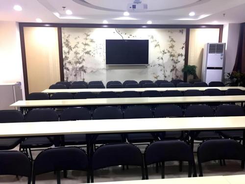 a conference room with tables and chairs and a screen at Jinjiang Inn Handan Zhonghua Nan Street Xueyuan Bei Road in Handan