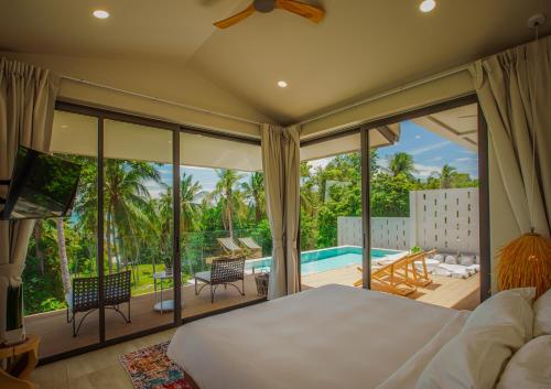 a bedroom with a large bed and a balcony with a pool at Treetop Bliss Villa by Sea N' Rent in Koh Phangan