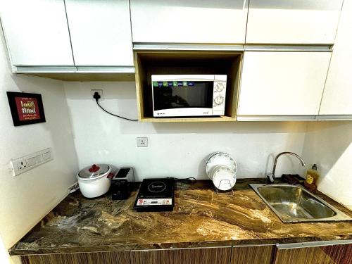 een aanrecht met een magnetron en een wastafel bij luxury studio sector 74 in Noida