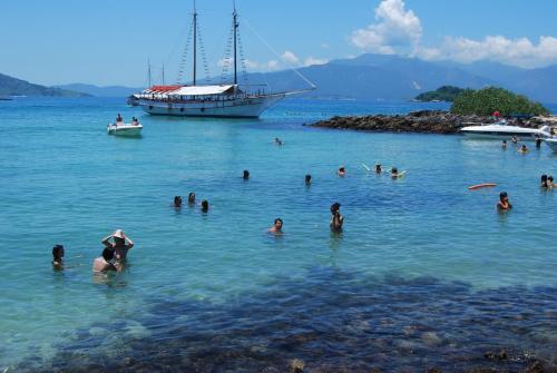 a group of people in the water with a boat at Pousada Agua Viva in Abraão