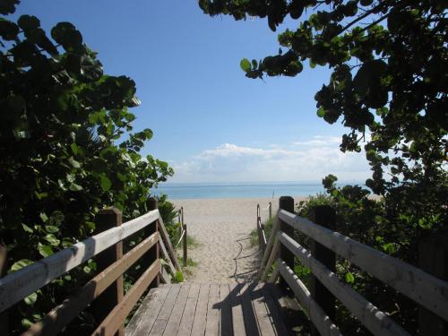 a wooden pathway to the beach with the ocean in the background at Ocean Breeze in Miami Beach