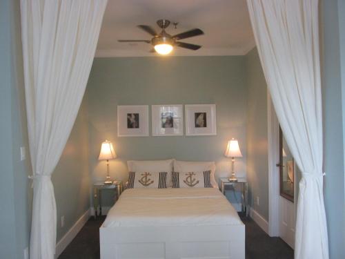 1 dormitorio con 1 cama con cortinas y ventilador de techo en Ocean Breeze, en Miami Beach