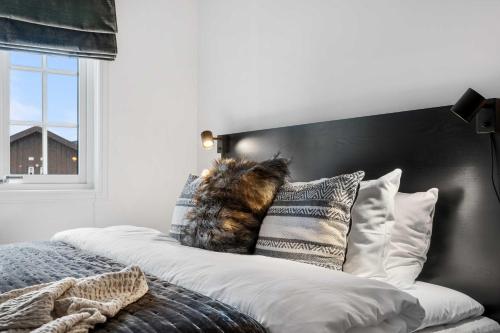 a cat sitting on top of a bed with pillows at Fjellvangvegen 11 by Vacation Trysil in Trysil