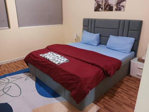 a bed with a red blanket and blue pillows at Splendid 3-Bedroom Apartment near Buhaira Corniche in Sharjah