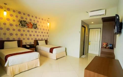 ein Hotelzimmer mit zwei Betten und einem Fernseher in der Unterkunft Mataram Square Hotel in Tanjungkarang
