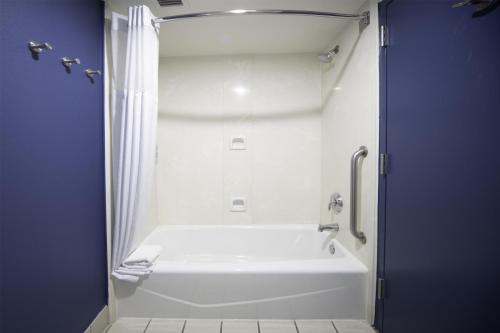 une baignoire blanche dans une salle de bain avec un mur bleu dans l'établissement Spark by Hilton Amarillo East, à Amarillo