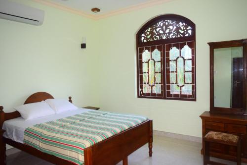 a bedroom with a bed and a stained glass window at Sri Lagoon Villa in Negombo