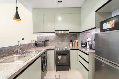 a kitchen with white cabinets and a stainless steel appliance at ALiving Elegant 1BR I Golf Gate, DAMAC Hills in Dubai