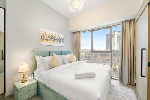 a bedroom with a large bed and a large window at ALiving Elegant 1BR I Golf Gate, DAMAC Hills in Dubai