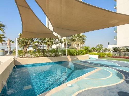 a swimming pool with an umbrella over a building at ALiving Elegant 1BR I Golf Gate, DAMAC Hills in Dubai