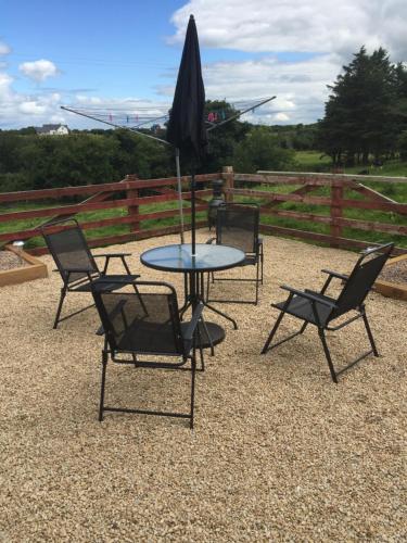 a table and chairs and an umbrella on a patio at Bun An Coirin in Clonbur