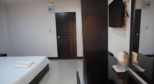 ein kleines Zimmer mit einem Bett und einer schwarzen Tür in der Unterkunft MT Place in Sakon Nakhon