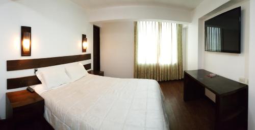 a bedroom with a white bed and a television at La Cabaña Hotel in Cusco