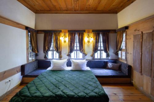 a bedroom with a green bed and windows at Gulevi Safranbolu Heritage Hotel in Safranbolu