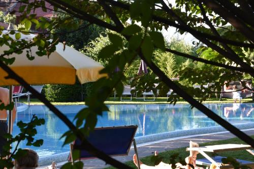 a swimming pool with a chair and an umbrella at Angerburg Blumenhotel in Appiano sulla Strada del Vino