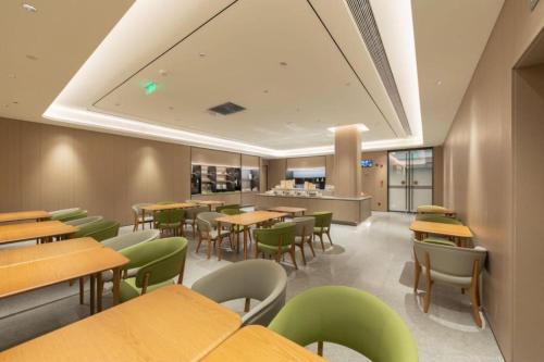 a restaurant with wooden tables and green chairs at Ji Hotel Beijing Daxing Airport Safari Park in Beijing