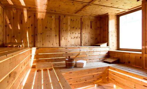 a wooden sauna with a bench and a window at Dolomitenhotel Weisslahnbad in Tires