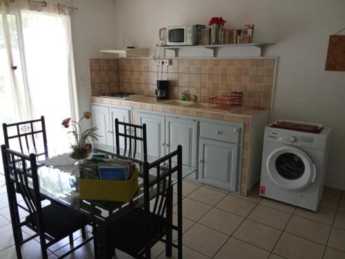 cocina con mesa y lavadora en Residence Virginie, en Saint-Leu