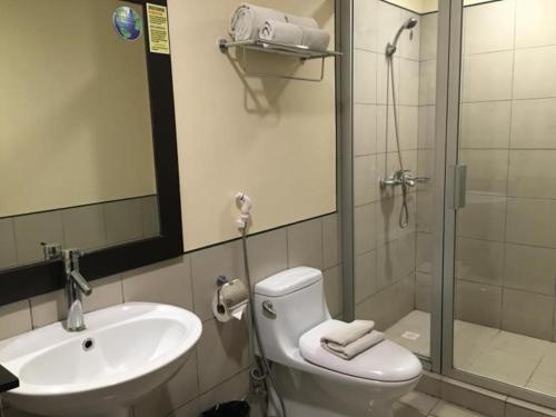 une salle de bain avec toilettes, lavabo et douche dans l'établissement Baguio Burnham Suites Hotel, à Baguio