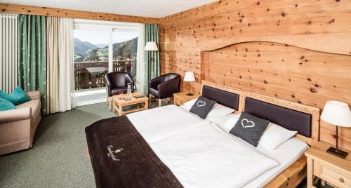 a bedroom with a bed with a wooden wall at Hotel Continental in Selva di Val Gardena