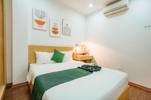 a bedroom with a large white bed with green accents at XÔI Setai Suites Linh Lang in Hanoi
