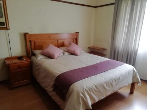 1 dormitorio con 1 cama grande y 2 almohadas rosas en Green Trees Cottage, en Nelspruit