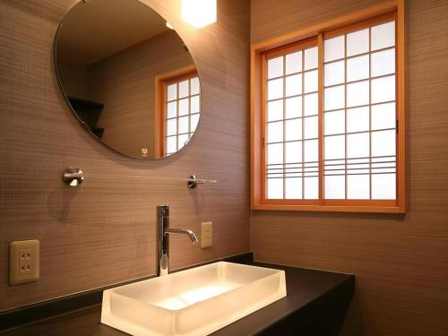 ein Badezimmer mit Waschbecken und Spiegel in der Unterkunft Suigetsurou Hotel in Tonami
