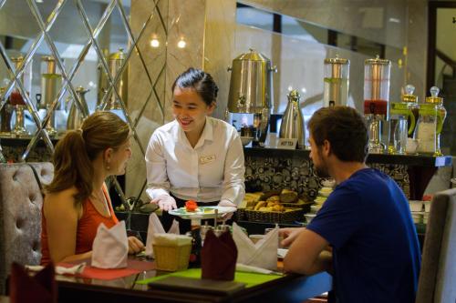 a woman holding a plate of food in a restaurant at Ambassador Hanoi Hotel & Spa in Hanoi