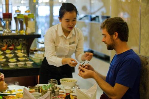 a woman serving a man a plate of food at Ambassador Hanoi Hotel & Spa in Hanoi