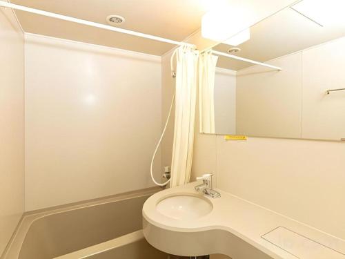 une salle de bain avec toilettes, lavabo et miroir dans l'établissement Tabist Yabuki Station Hotel, à Yabuki
