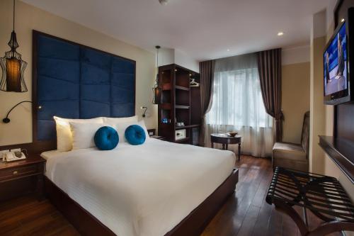 a bedroom with a large white bed with blue pillows at Ambassador Hanoi Hotel & Spa in Hanoi