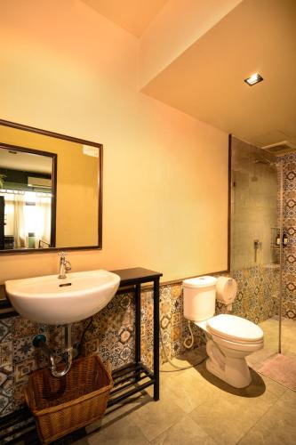 a bathroom with a sink and a toilet and a mirror at Niras Bankoc Hostel in Bangkok