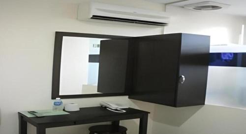 a mirror on a wall with a table and a stool at Rafayeh Hotel in Kampong Lobok