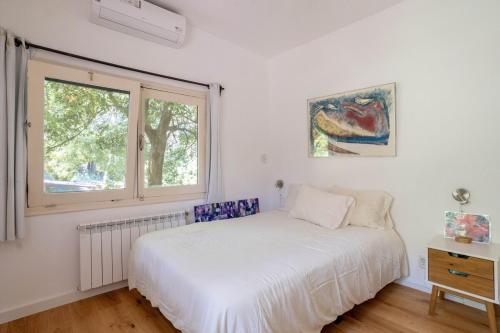 PURA VIDA - Amazing Villa with 4 bedrooms for up to 11 guests close to beach في بونتا دل إستي: غرفة نوم بيضاء مع سرير ونافذة