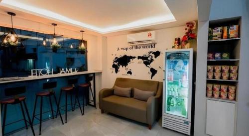 a kitchen with a bar with a couch and a refrigerator at Kimal Hotel Taiping in Taiping