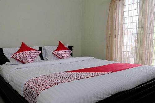 Un dormitorio con una cama con almohadas rojas y blancas. en Hotel O Abz Guest House Syariah, en Jambi