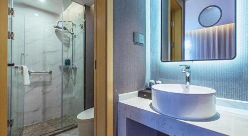 une salle de bain avec un lavabo et une douche en verre dans l'établissement Jinjiang Inn Wuhan Linjiaohu Wanda Branch, à Wuhan