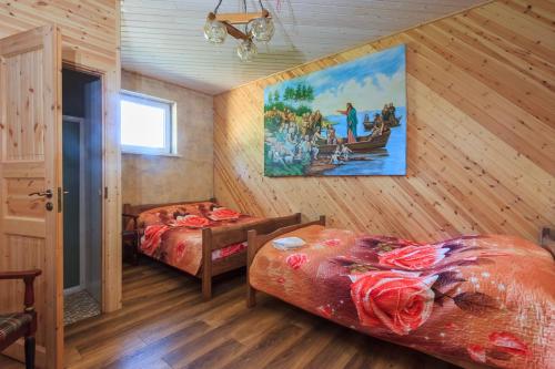 a bedroom with two beds and a painting on the wall at Vilkdvaris in Plungė