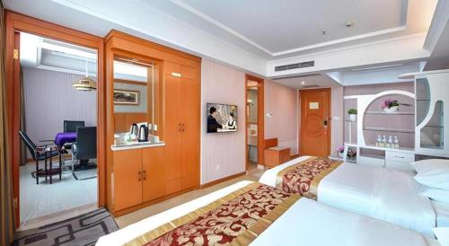 ein Hotelzimmer mit großem Bett und Schreibtisch in der Unterkunft Vienna Hotel Guangzhou Tianhe South China Botanical Garden Metro Station in Guangzhou