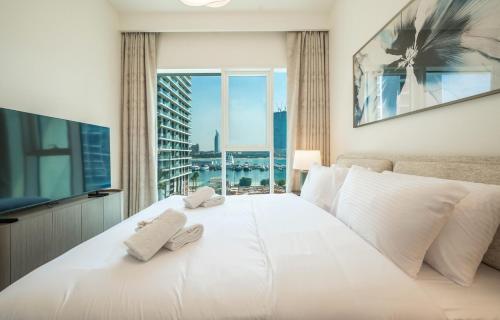 a bedroom with a large white bed with a large window at Zapbed House -Elegant 1 BR Apartment Grand Bleu Emaar Beachfront in Dubai