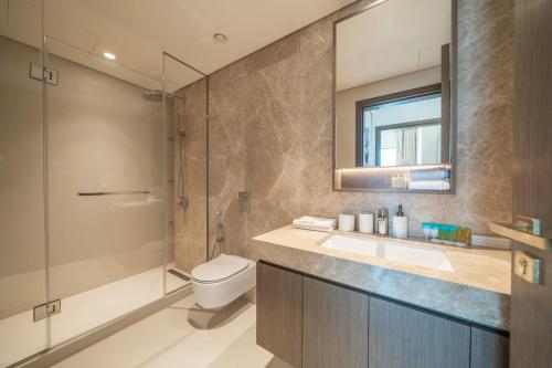 a bathroom with a toilet and a sink and a shower at Zapbed House -Elegant 1 BR Apartment Grand Bleu Emaar Beachfront in Dubai