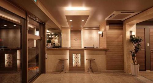 a lobby with two stools and a bar in a building at Ryuka Hotel Naha in Asato
