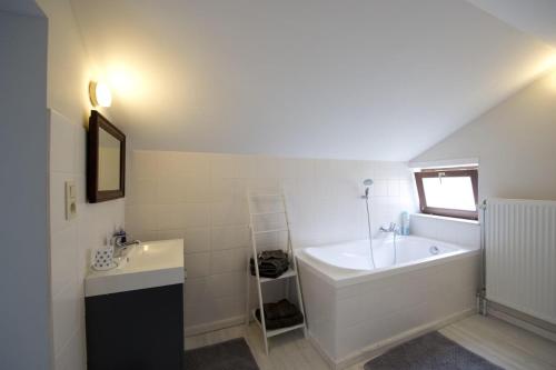 Baño blanco con bañera y lavamanos en Guesthouse Biolleke, en Boutersem