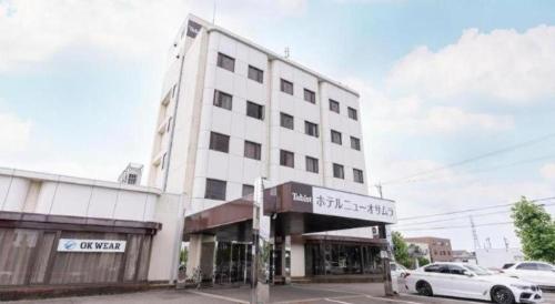 un bâtiment blanc avec une voiture garée devant dans l'établissement Tabist Hotel New Osamura Sabae, à Sabae